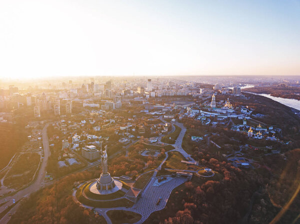 Panoramic photography from the drone, bird's eye view to historical famous places in Kiev, Dnieper River and to the left bank of city with modern buildings at sunset in the summer.