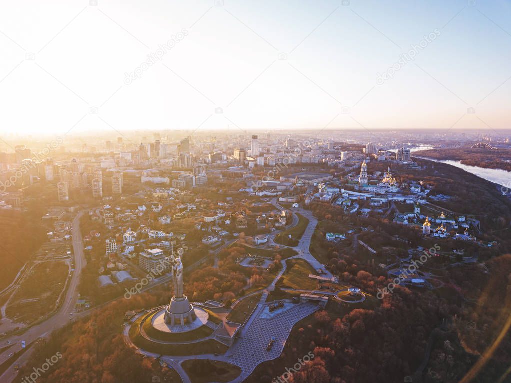 Panoramic photography from the drone, bird's eye view to historical famous places in Kiev, Dnieper River and to the left bank of city with modern buildings at sunset in the summer.