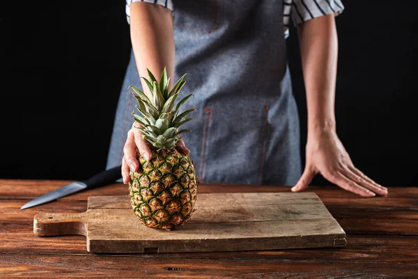 Girl Apron Holds Organic Pineapple Wooden Board Brown Table Dark — Stock Photo, Image