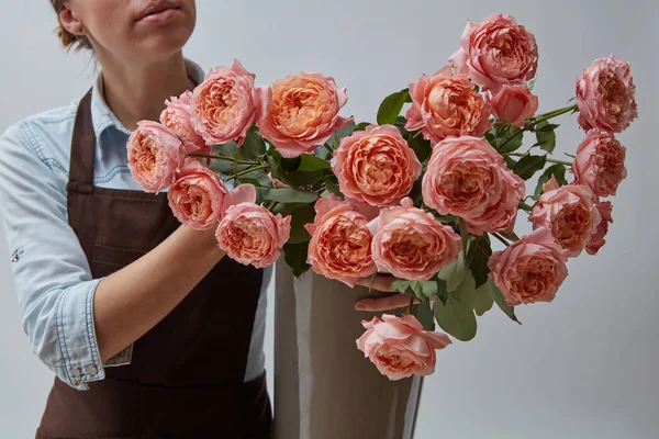 花瓶にピンクのバラ 女性の花屋は 灰色の背景の周りの手に花と花瓶を保持しています フラワー ショップのコンセプト — ストック写真