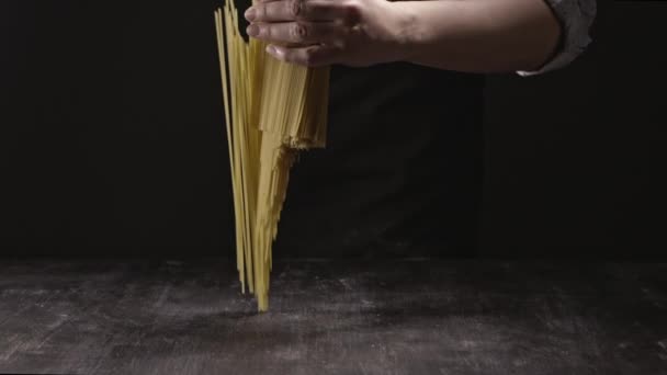 暗い背景の女性の手にスパゲティの束 イタリア料理の概念 — ストック動画