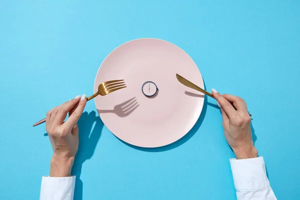 圆观六点钟和女人的手与叉子和刀在女孩的手在蓝色背景与阴影 减肥时间 饮食控制或饮食概念 文本的位置 — 图库照片