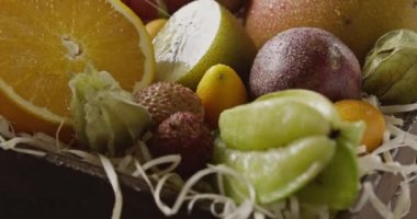 Jucy ahşap arka plan kutusunda taze tropikal meyve. Passion fruit, carambola, mango, Çin, Kamkat, yarım turuncu, phisalis 