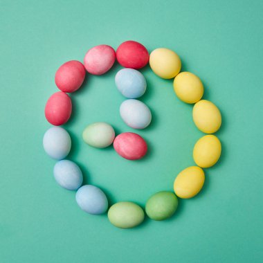 Metin için yer ile yeşil bir arka plan üzerinde renkli renkli yumurta yapılmış bir saat. Paskalya kavramı. Düz yatıyordu