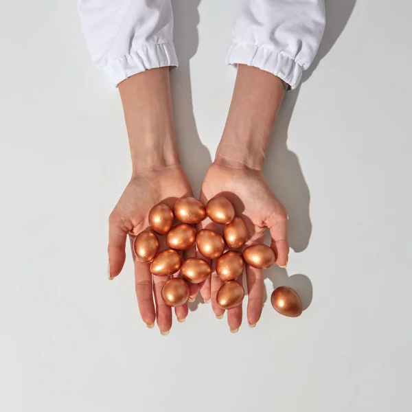 Сірому Тлі Руки Дівчини Тримають Багато Пофарбованих Золотих Яєць Копіювати — стокове фото