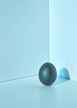 Gölgeler ve kopya alanı ile mavi bir arka plan üzerinde sunulan koyu mavi renkli yumurta. Paskalya düzeni