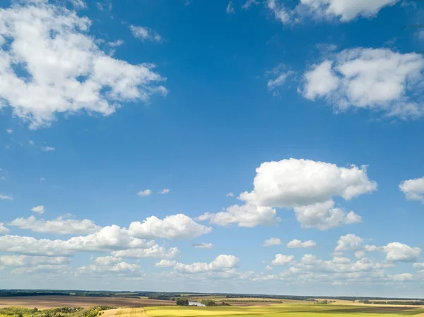 Amazing landscape with fields, lands on a background of blue cloudy sky in a summer day. Aerial view from drone.