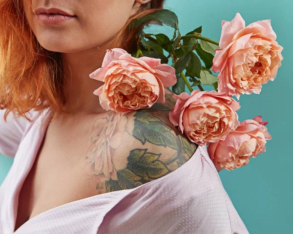 美丽的红发女人与活珊瑚色的花朵在她的肩膀与纹身玫瑰在蓝色的背景 母亲节或妇女节的问候节日卡 — 图库照片