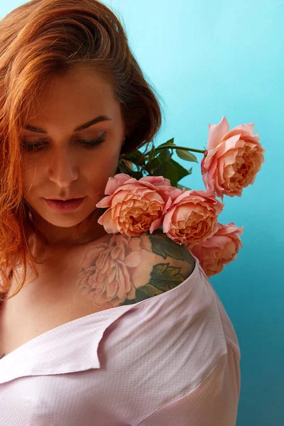 新鲜的自然生活珊瑚色玫瑰的肩膀上的好女人与纹身和生姜头发在蓝色的背景 母亲节或妇女节的概念 — 图库照片