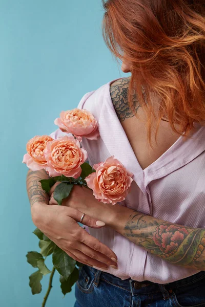 一位有纹身的年轻女子手里拿着一束粉红色的玫瑰 周围是蓝色的背景 有复制空间 母亲节概念 — 图库照片