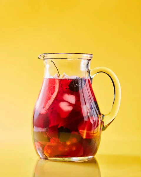 コピースペース付きの黄色い背景にガラスのジャグで作りたてのベリーフルーツドリンク 夏のビタミン飲料 — ストック写真