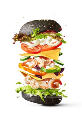 Kopya alanı ile beyaz bir arka plan üzerinde uçan malzemeler karides, taze organik sebze ve siyah topuz Ev yapımı lezzetli sandviç.