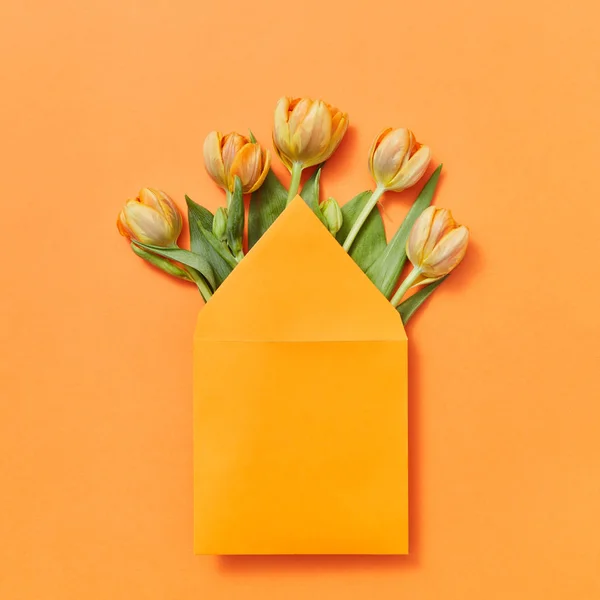 春の新鮮な花のチューリップは コピースペースと黄色の背景にクラフトエンベロープで グリーティング カード — ストック写真