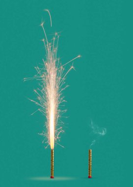 Burning firework with bright sparkes and smoke from burnt candle on a turquoise background, copy space. Concept of festive event.