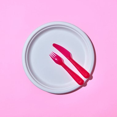 Kopya alanı ile açık pembe arka plan üzerinde plastik renkli sofra yemek seti. Üstte görüntü.