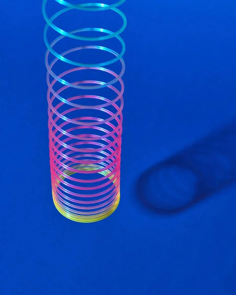 Stretching Rainbow Plastic Slinky Toy Boven Blauwe Achtergrond Met Schaduwen — Stockfoto