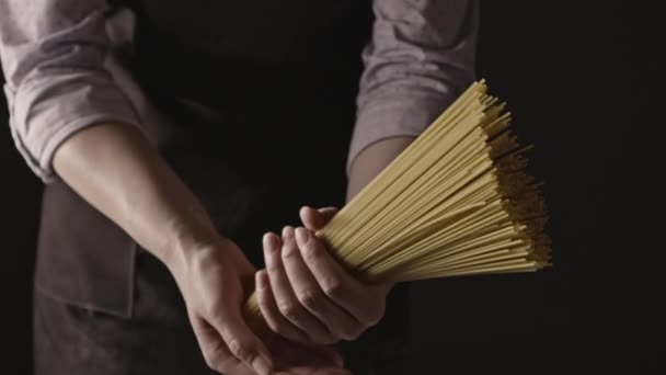 暗い背景の女性の手にスパゲティの束 イタリア料理の概念 — ストック動画