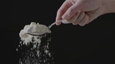 Kadın eli kaşıkla un hazırlıyor, hamur yoğuruyor.