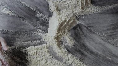 Kadın elleri masada un hazırlıyor, hamur yoğuruyor.