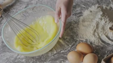 Kadın çırpılmış yumurta sarısı çırpıyor, hamur yoğurmaya hazırlanıyor.