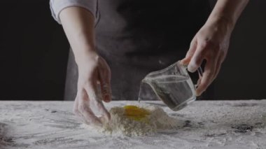 Kadın fırıncı hamur yoğurmak için su ekliyor