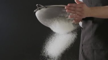 Kadın elleri unu süzgeçten geçirir, hamur yoğurur.