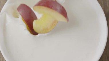  Dilimlenmiş şeftali kaseye süt ve video ile düşüyor. 