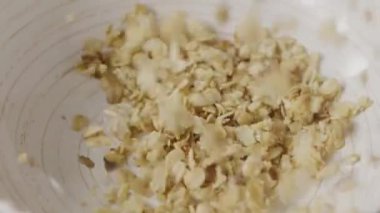 Yulaf ezmesi tanecikleri tabağa düşüyor. Diyet vejetaryen organik gıda kavramı.