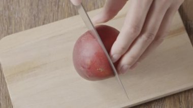 Taze olgun şeftali hazırlama videosu, kadın elleri tahta bir tahtada meyve dilimleri kesiyor. Ağır çekim, 2K video, 240 fps, 1080p.