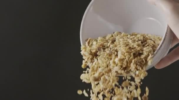 Granola d'avoine tombant dans l'assiette. Concept de régime végétalien alimentaire biologique.