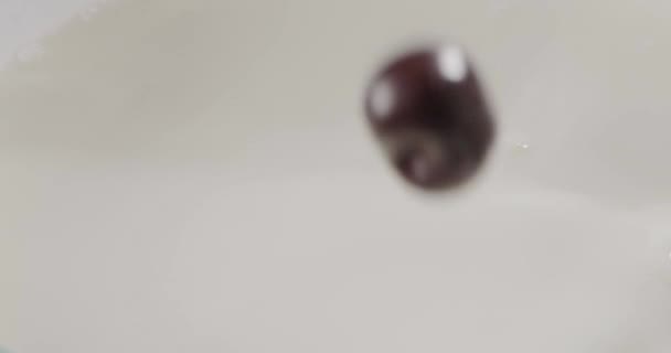 新鲜成熟的樱桃和切碎的桃与牛奶一起掉进碗里 — 图库视频影像