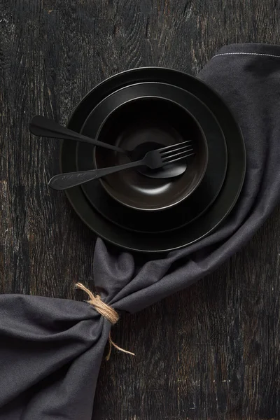 空の黒い台所用品から創造的な組成物 フォークとスプーンの皿やプレートは 同じ色の背景 コピースペースに繊維ナプキンを提供しました トップ表示 — ストック写真