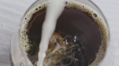 Sütlü kahve. Süt bir bardak kahveye dökülür..