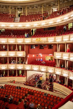 Beautiful and rich decoration of interior the Vienna State Opera auditorium with parterre and balconies and people before starting performance in Vienna, Austria. clipart