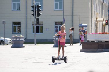 Tyumen, Rusya, 15 Temmuz 2018: Rus kız meydanda yaz aylarında bir giroskuter sürmek