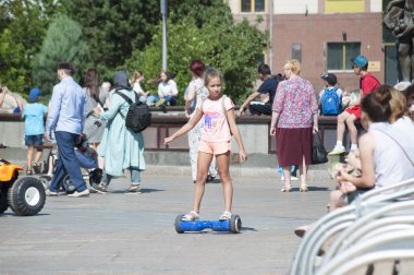 Tyumen, Rusya, 15 Temmuz 2018: Rus kız meydanda yaz aylarında bir giroskuter sürmek.