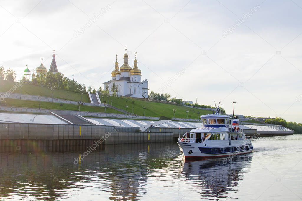Tura River Embankment in Tyumen, Russia. Holy Trinity Monastery and the motor ship with tourists