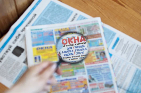 Leer los periódicos rusos por medio de una lupa . — Foto de Stock