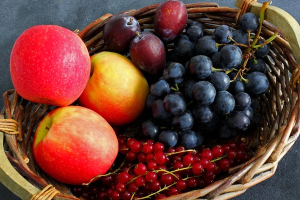 Variety of fresh fruits in market basket on dark background