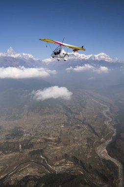 Ultralight plane and trike fly over Pokhara and Annapurna region in Nepal. Machapuchare summit clipart