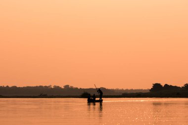 Erkekler bir nehir siluet günbatımı ışığı ile bir teknede
