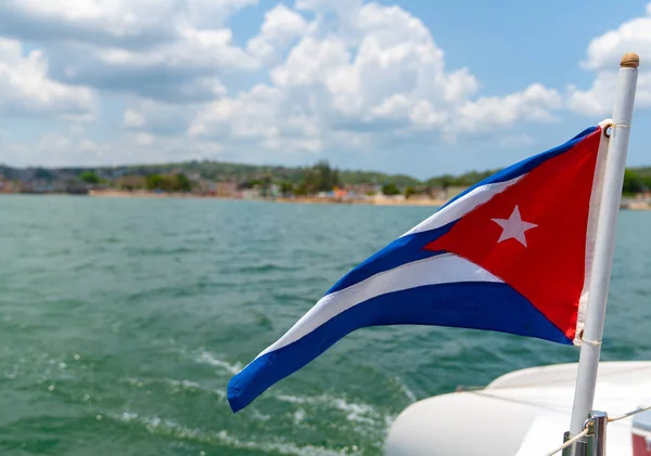 Cuba flag waving on boat at sea near Cuban coastline — Stock Photo, Image