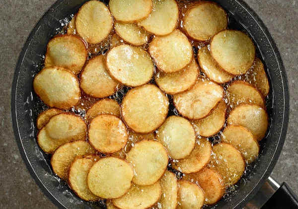 煎土豆在平底锅与油 上部看法 — 图库照片