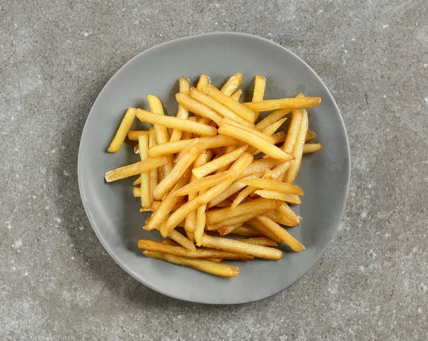 plate of french fries on grey kitchen table, top view