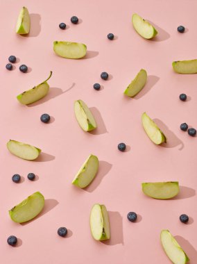 pembe arka plan üzerinde elma parçaları ve yaban mersini