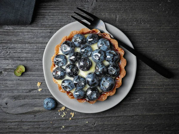 Blueberry tart on dark wooden table — Stock Photo, Image