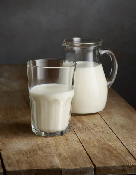 Milk jug and glass on wooden table — Stock Photo, Image