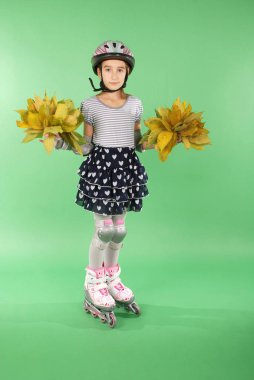 Yeşil arka planı izole rollerskates güzel kızla. O sonbahar yaprakları tutar