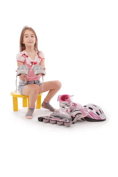 学校の魅力的な木の葉髪女の子年齢短いジーンズのショート パンツとピンク シャツの椅子に座って 足をローラー スケートしようとします 白い背景に分離 — ストック写真