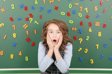 Kız bir yeşil okul yönetimi mıknatıslar yeşil zemin üzerine düşüncelerini tasvir sayıların önünde duruyor